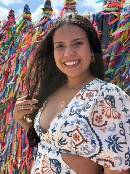 Viajante sorrindo diante das fitas do Senhor do Bonfim