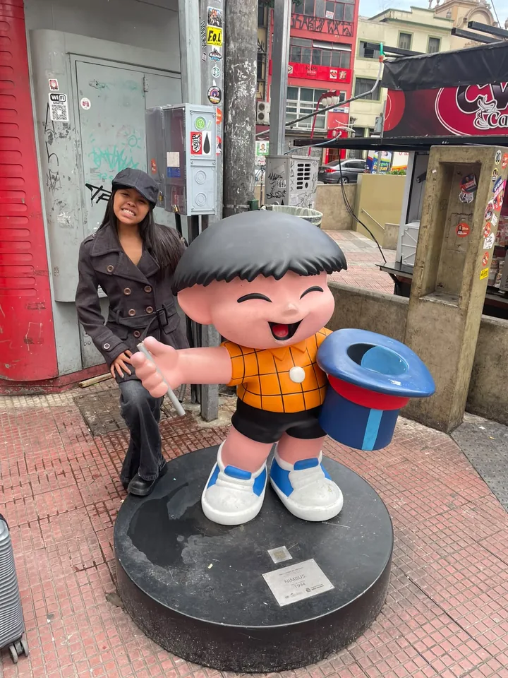 Cliente Quero+ Viagens posando ao lado de escultura colorida em rua de São Paulo